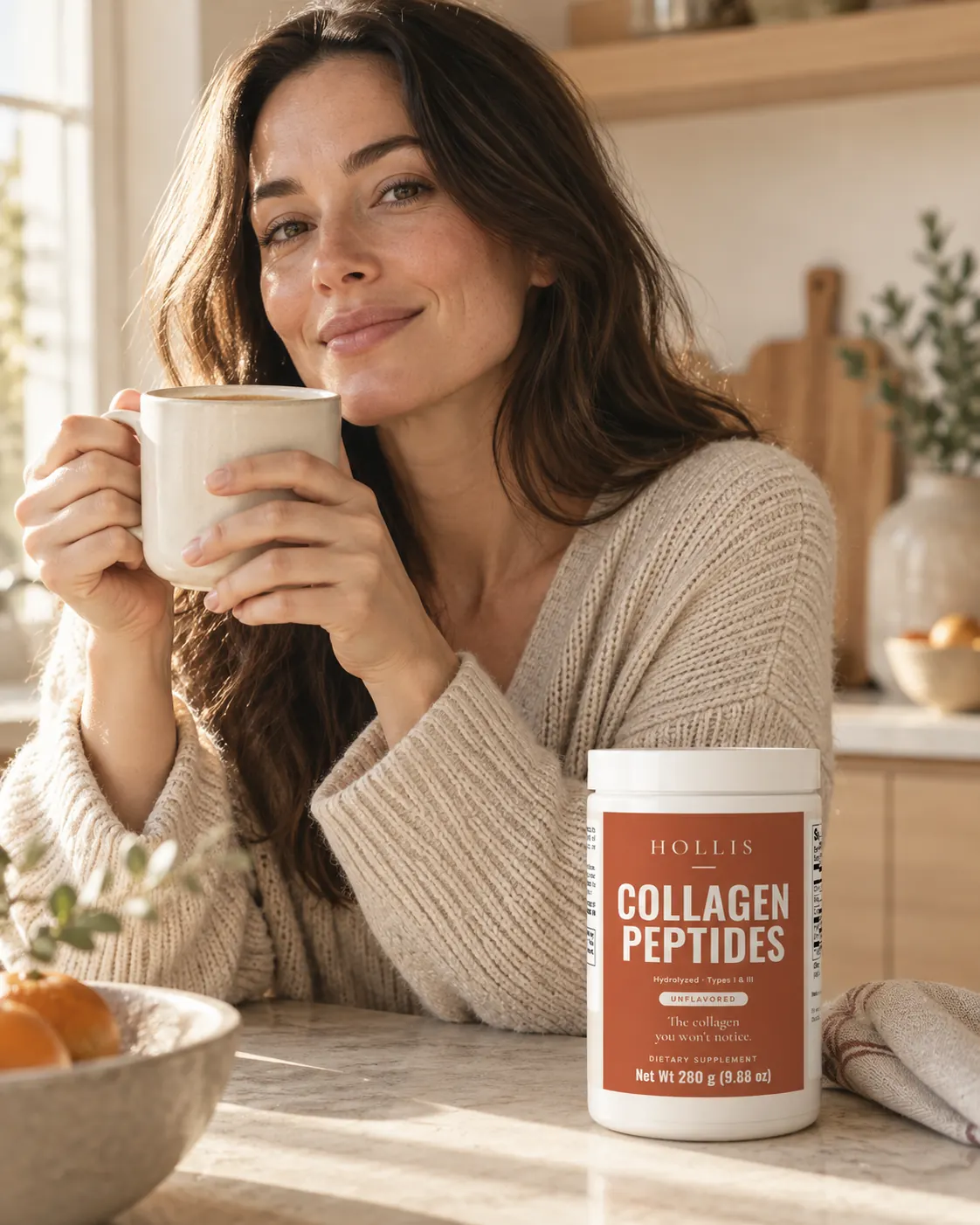 A woman holding a mug in a sunlit kitchen, the Hollis container on the counter
