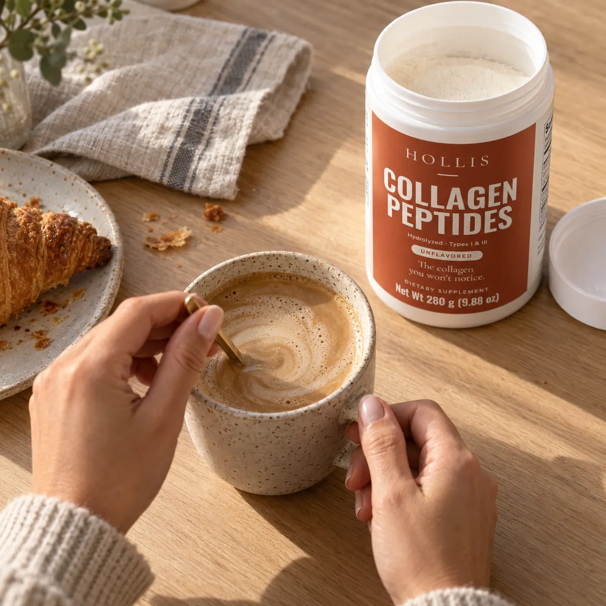 Hands stirring a mug of coffee beside the Hollis container